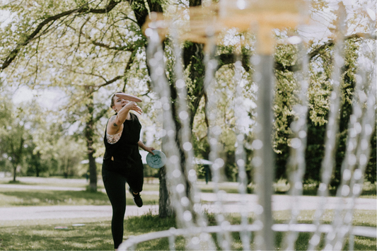 disc golf player throwing a golf frisbee into disc golf basket demonstrating disc golf grip
