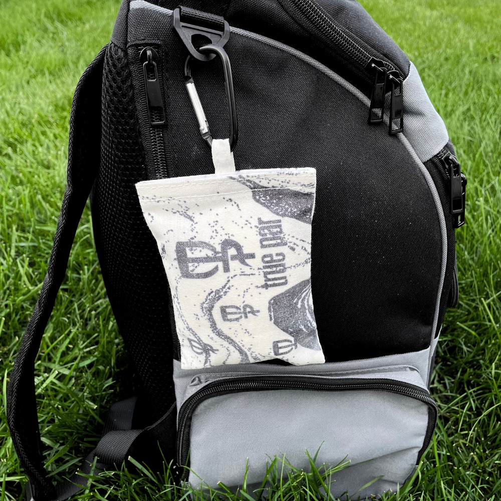 A grip bag for disc golf with carabiner attached to disc golf disc backpack